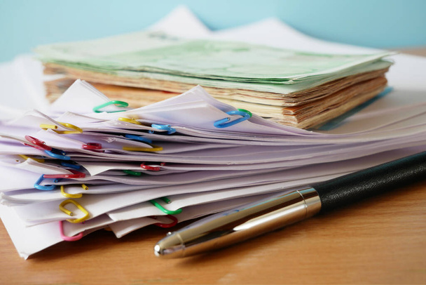 dinheiro com grande pilha de documentos com grampos de aglutinante na mesa de madeira, close-up - Foto, Imagem