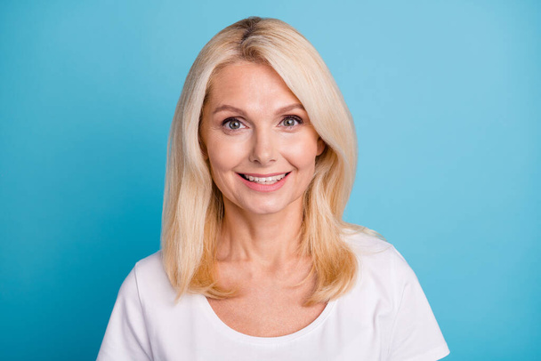 Fotografie veselý středního věku dáma žena usmívá perfektně upravené trámce nosí bílé tričko izolované modré barvy pozadí - Fotografie, Obrázek
