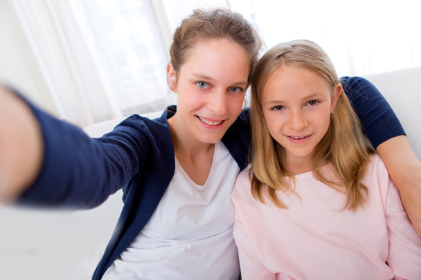 Attractive woman and little sister taking selfie - Foto, imagen