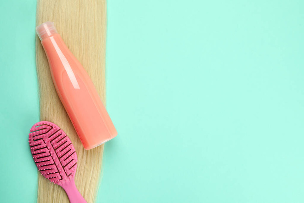 Female hair with shampoo and hairbrush on mint background - Photo, Image
