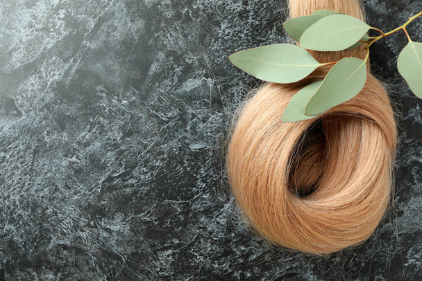 Волосы женского пола с веткой растений на темном фоне - Фото, изображение
