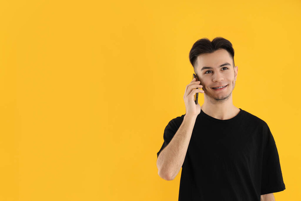 Молодий чоловік говорить по телефону на жовтому фоні
 - Фото, зображення