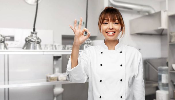 happy female chef showing ok hand sign on kitchen - Foto, afbeelding