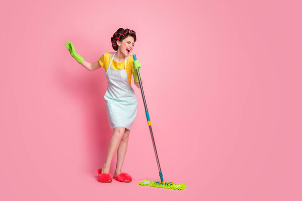 Full length body size view of lovely glad cheerful maid singing hit song using mop like mic having fun isolated on pink color background - 写真・画像