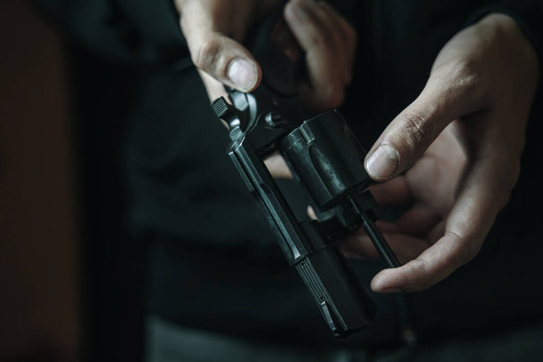 Mens hands check for bullets in revolver barrel. - Foto, afbeelding
