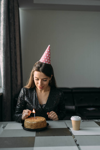 Caucasian girl lighting candle on cake, birthday at home, lonely woman celebrating anniversary with cake, introvert quarantine social distance, birthday celebration concept - Photo, Image