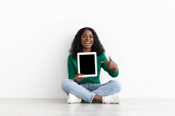 Ελκυστική μαύρη γυναίκα που δείχνει μοντέρνο ψηφιακό tablet με άδεια οθόνη - Φωτογραφία, εικόνα