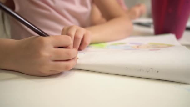 Het kind tekent met gekleurde potloden. Close-up tekeningen van het kind. Een meisje in een roze T-shirt tekent een plaatje - Video
