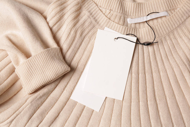 Blank white tags on beige sweater, top view. Space for text - Фото, зображення