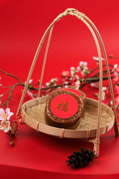 Chinese New Year Cake (with Chinese character "Fu" means Fortune). Popular as Kue Keranjang or Dodol China in Indonesia. Served on Bamboo Plate, Imlek Flower Decoration, Copy Space for Text - Photo, Image