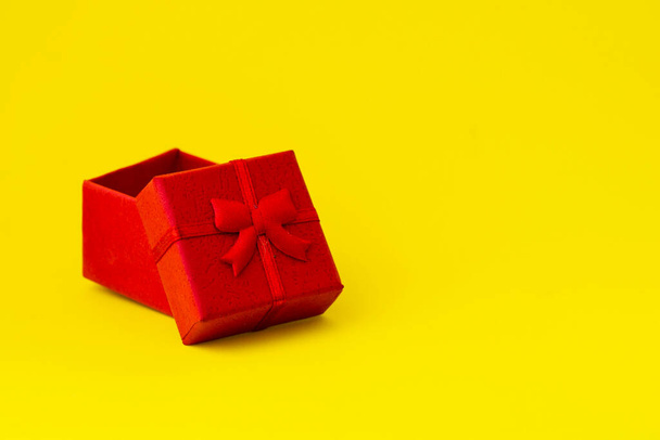 piros ajándékdoboz nyitott fedéllel, sárga háttérrel, másoló felülettel. Kiváló minőségű fénykép - Fotó, kép