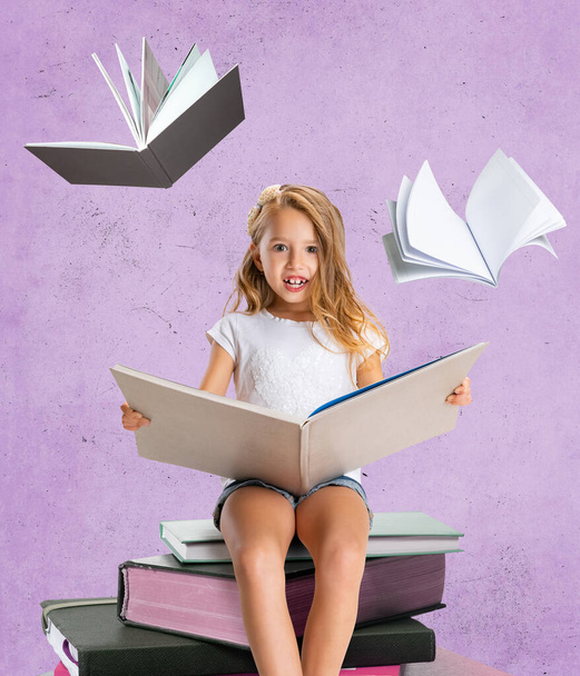 Creative design, modern art collage of beautiful little girl, child sitting on stack of books and reading isolated over purple background - Valokuva, kuva
