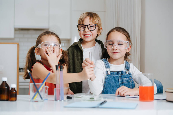 Lively little kids doing home science project, passing a flask - Photo, image