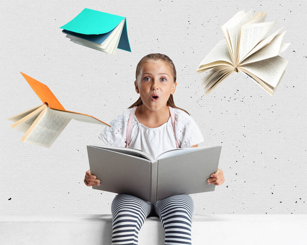 Creative collage of surprised girl sitting and reading around flying books isolated over light gray background - 写真・画像