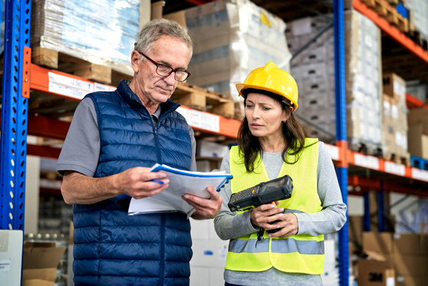 Two caucasian workers in mature age discussing together in warehouse                                 - Foto, Bild
