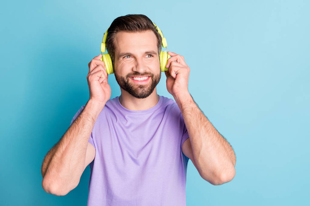 Photo of young handsome man dream dreamy look empty space listen enjoy music earphones isolated over blue color background - Foto, immagini