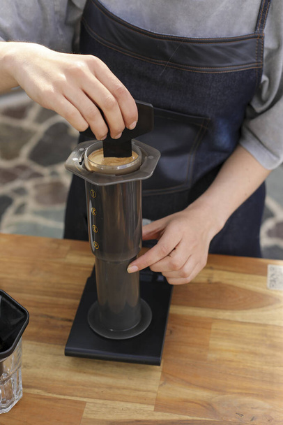 A vertical shot of a barista making coffee with a manual coffeemaker on a food weight scale - Photo, image