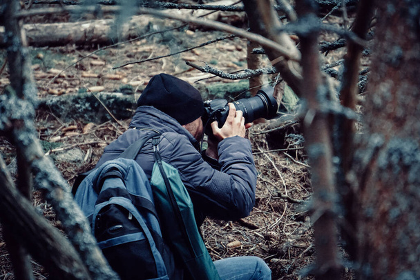 A view of a photographer taking pictures in a forest - Fotó, kép