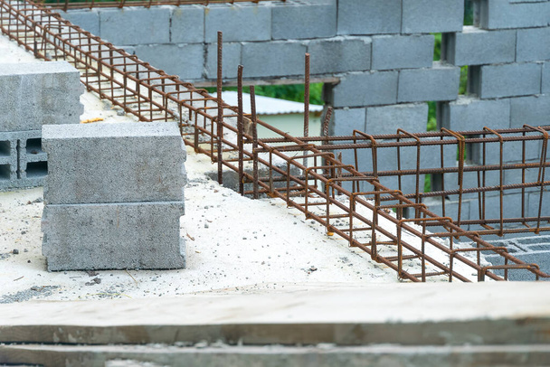 Close-up of blocks and fittings on a construction site. Stages of construction. House is made of cinder blocks with protruding fittings, ground floor. - Photo, Image
