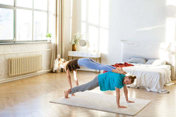 Young couple practicing acro yoga at home on the floor. - Photo, Image