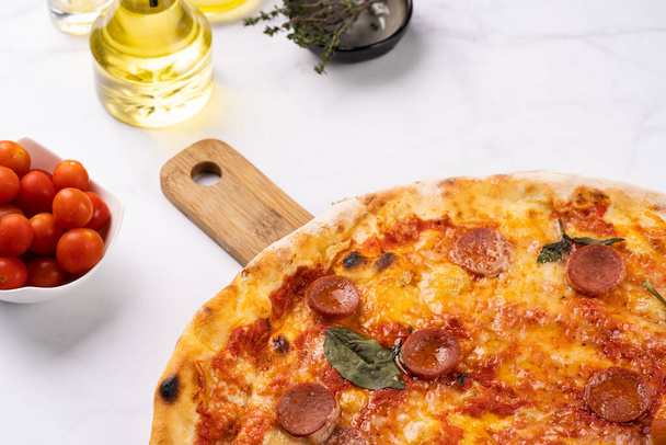 Čerstvě upečená tradiční středomořská pizza s rajčatovou omáčkou marinara, sýrem mozzarella, vepřovou klobásou salsiccia a bazalkou - Fotografie, Obrázek