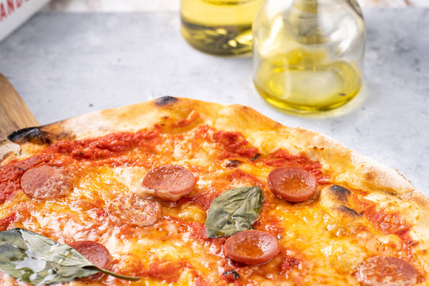 Świeżo upieczona tradycyjna śródziemnomorska pizza z sosem pomidorowym marinara, serem mozzarella, salsiccia z kiełbasą wieprzową i bazylią - Zdjęcie, obraz
