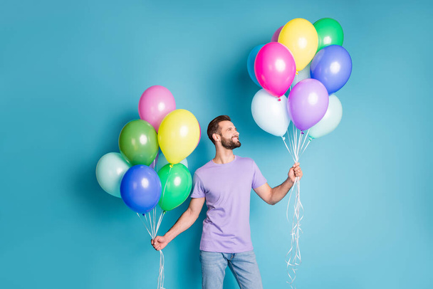 Photo portrait of guy holding helium balloons in two hands isolated on pastel blue colored background - Foto, imagen