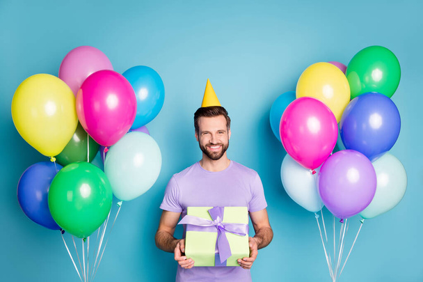 Photo portrait of smiling man holding wrapped gift box isolated on pastel blue colored background - Foto, Imagem