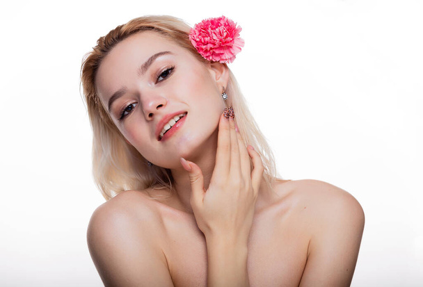 Okouzlující mladá žena s růžovou květinou. Blonďatý model drží růžový květ za uchem izolované přes bílé pozadí. Koncept krásy a zdravotní péče volný prostor pro text - Fotografie, Obrázek