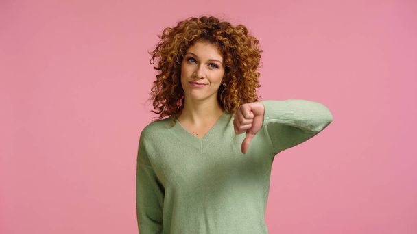 displeased redhead woman looking at camera and showing dislike isolated on pink - Photo, image