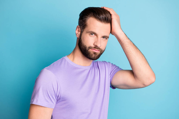 Photo of young handsome man happy enjoy hands touch hair new hairdo wear violet t-shirt isolated over blue color background - Zdjęcie, obraz