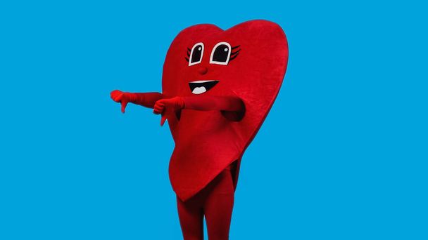 persona en traje de corazón rojo mostrando pulgares hacia abajo aislado en azul  - Foto, Imagen