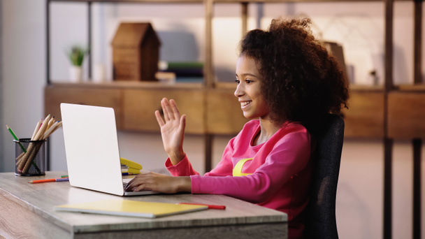幸せなアフリカ系アメリカ人の子供がノートパソコンでビデオチャットをしながら手を振って - 写真・画像