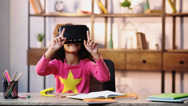 happy african american child in vr headset gesturing while sitting at desk - Foto, immagini