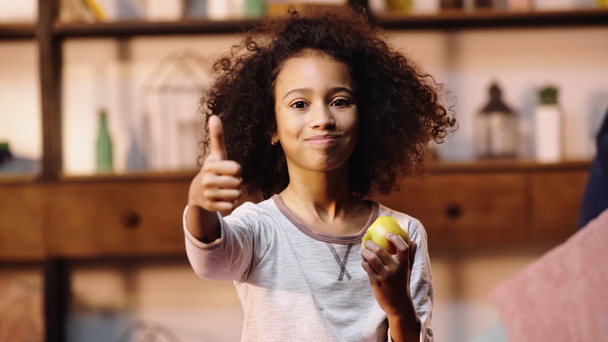 african american child showing thumb up while eating apple - Photo, Image