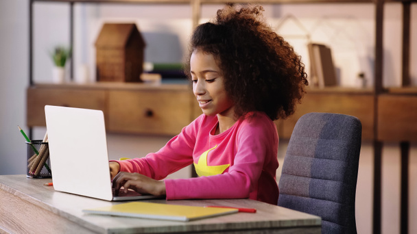 niño americano africano feliz usando el ordenador portátil mientras que hace la tarea  - Foto, Imagen