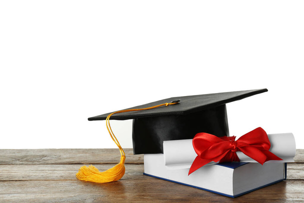 Graduation hat, book and diploma on wooden table against white background - Foto, Bild