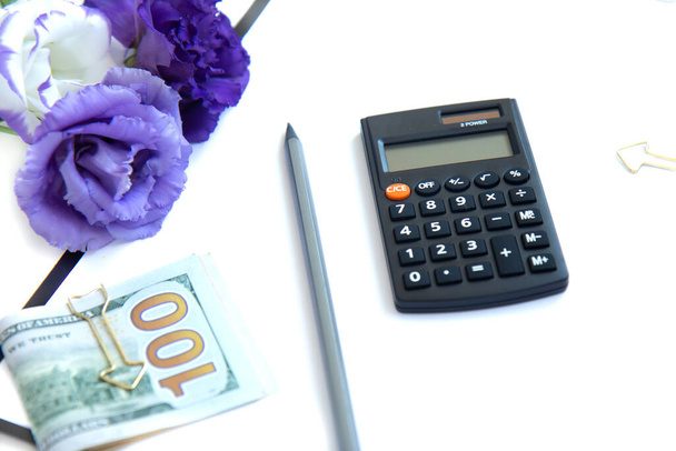 Clipboard with blank paper, calculator, paper money and purple flowers isolated on white background. Female workplace. Payment of taxes and investing - Photo, Image