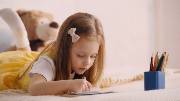 Child drawing near color pencils in bedroom  - Photo, Image