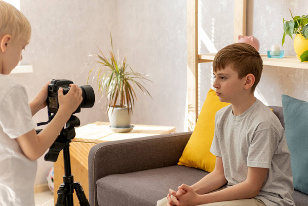 Друзья детей записывают видео на камеру в гостиной. Мальчик-подросток принимает блоги. Детский блогер - Фото, изображение
