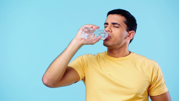 young man drinking water from bottle isolated on blue - Photo, Image