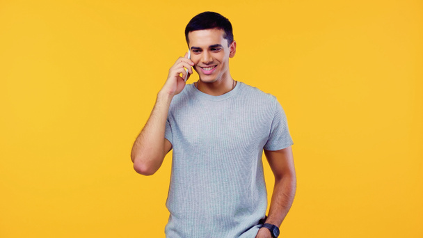 cheerful young man in t-shirt talking on cellphone isolated on yellow - Foto, Bild
