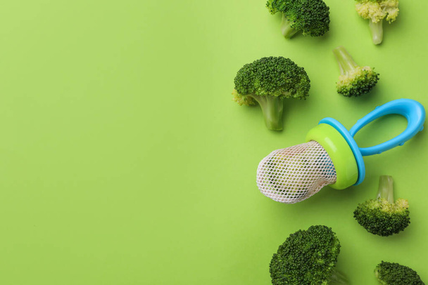 Nibbler with boiled broccoli on green background, flat lay. Space for text - Foto, imagen