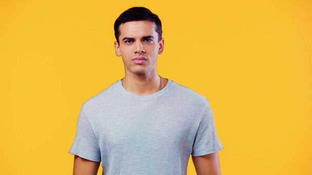 serious young man in t-shirt looking at camera isolated on yellow - Foto, afbeelding