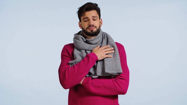 больной мужчина в розовом свитере и шарфе изолирован на голубом  - Фото, изображение