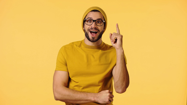 amazed young man in beanie hat showing idea sign isolated on yellow  - Foto, Bild