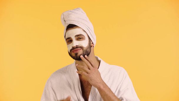 cheerful man with clay mask on face looking at camera isolated on yellow - Photo, image