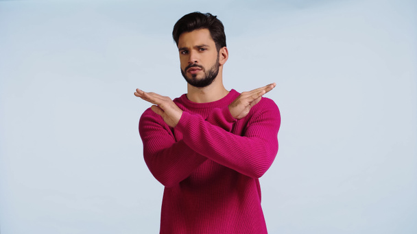 hombre serio en suéter rosa cruzando las manos aisladas en azul  - Foto, imagen