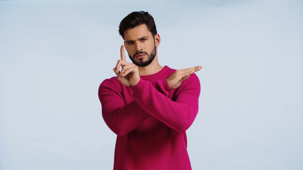 seriózní muž v růžovém svetru se zkříženýma rukama a ukazující prstem izolovaným na modré  - Fotografie, Obrázek