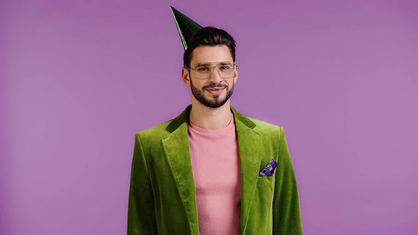 happy man in green jacket and party cap smiling isolated on purple - Foto, Imagem